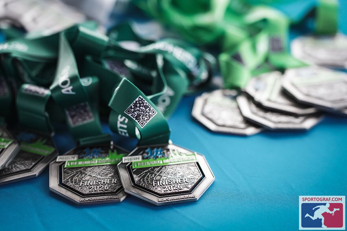 Mehrere Finisher-Medaillen liegen auf einem Tisch.